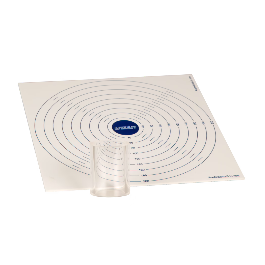 UZIN_Dummy_flow spread disc-mm_2017-09 Top-down, angled view of a rectangular white measuring mat printed with concentric circular measurement rings in millimetres. A blue circular logo marks the centre; radial numbers and short tick marks indicate distances (for example 40, 60, 80 up to 200 mm). A small transparent plastic cylinder sits near the lower centre of the mat and casts a faint shadow. The mat shows the label 'Ausbreitmaß in mm' in the corner; the scene is isolated on a white background and the mat is rotated so only part of the full circular grid is visible.